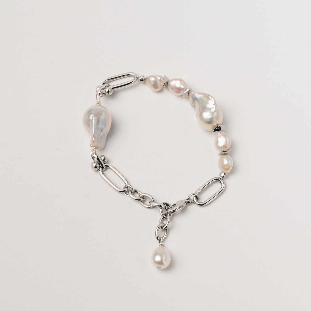 a white gold filled bracelet with two large baroque pearls and four small keshi pearls. There is a teardrop pearl attached to the end of the extender. The clasp is a lobster clasp.