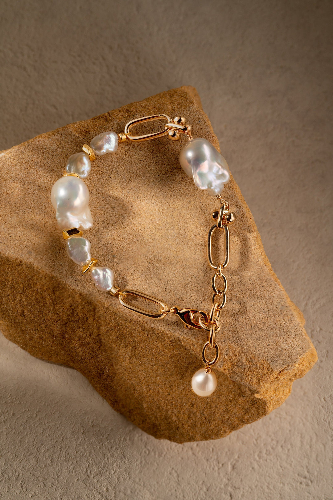a gold filled bracelet with two large baroque pearls and four small keshi pearls. There is a teardrop pearl attached to the end of the extender. The clasp is a lobster clasp.