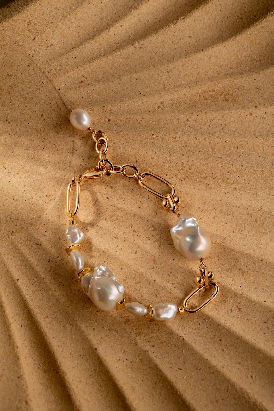 a gold filled bracelet with two large baroque pearls and four small keshi pearls. There is a teardrop pearl attached to the end of the extender. The clasp is a lobster clasp.