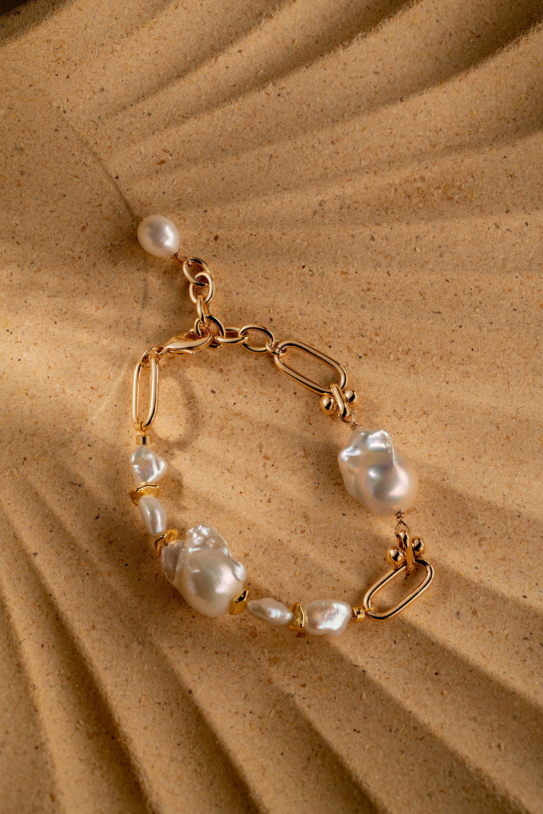 a gold filled bracelet with two large baroque pearls and four small keshi pearls. There is a teardrop pearl attached to the end of the extender. The clasp is a lobster clasp.
